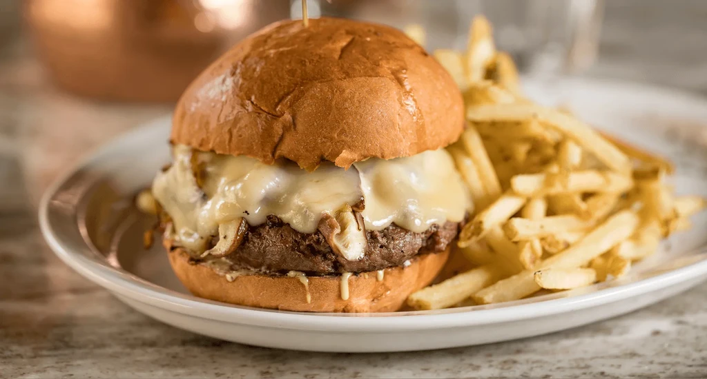 Beef burger with melted cheese, caramelized onions, and golden french fries.