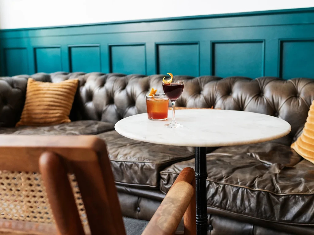 Amber and red cocktails on marble table in upscale lounge setting.