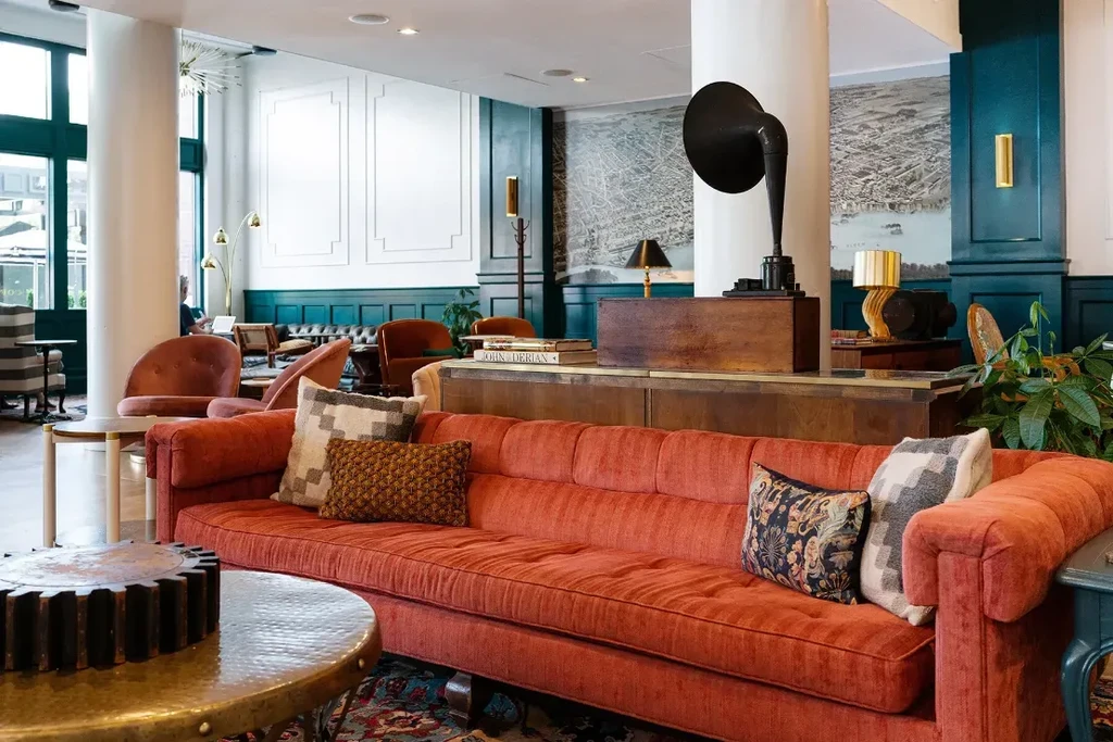 Rust-orange sofa, bronze table, phonograph, and old-world map mural.