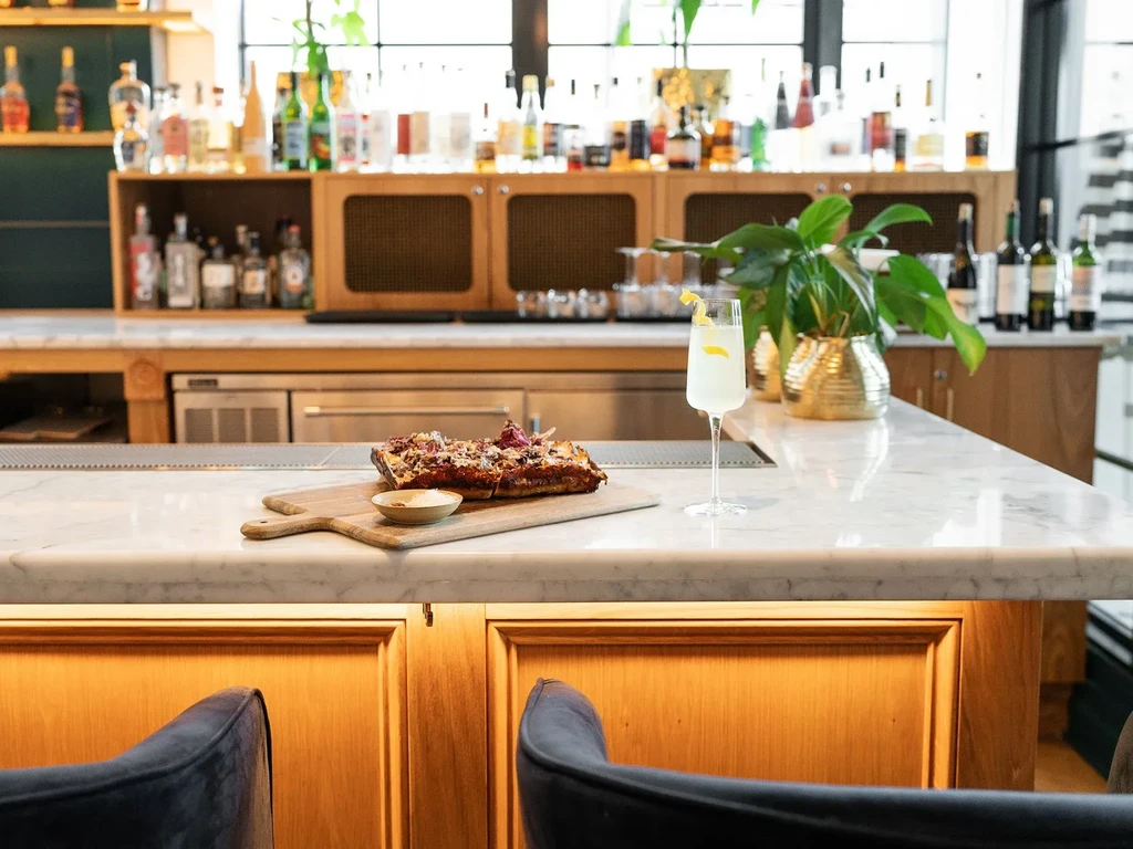 Flatbread and cocktail on a marble bar in an upscale restaurant.