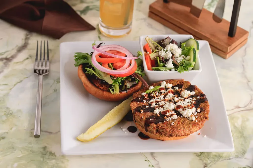 Overhead shot of an open-faced sandwich, green salad, and garnished patty.