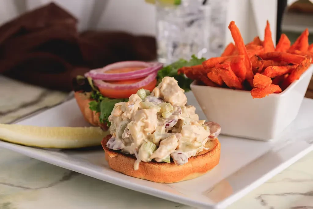 Open-faced chicken salad sandwich, sweet potato fries, and pickle spear.