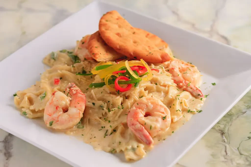 Creamy shrimp pasta with flatbreads, herbs, cheese, and colorful peppers.