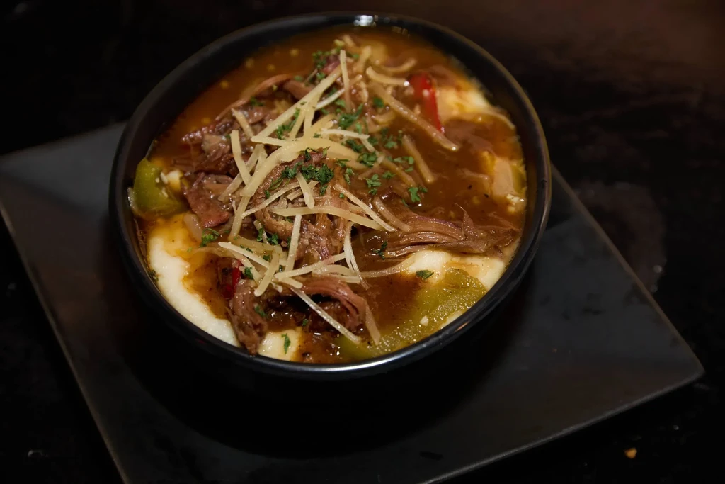 Braised meat and grits with peppers, cheese, and fresh herbs.