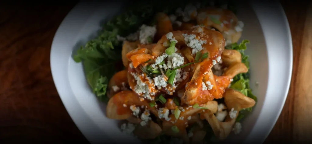 Overhead view of orange-sauced potato wedges, blue cheese, and green onions.
