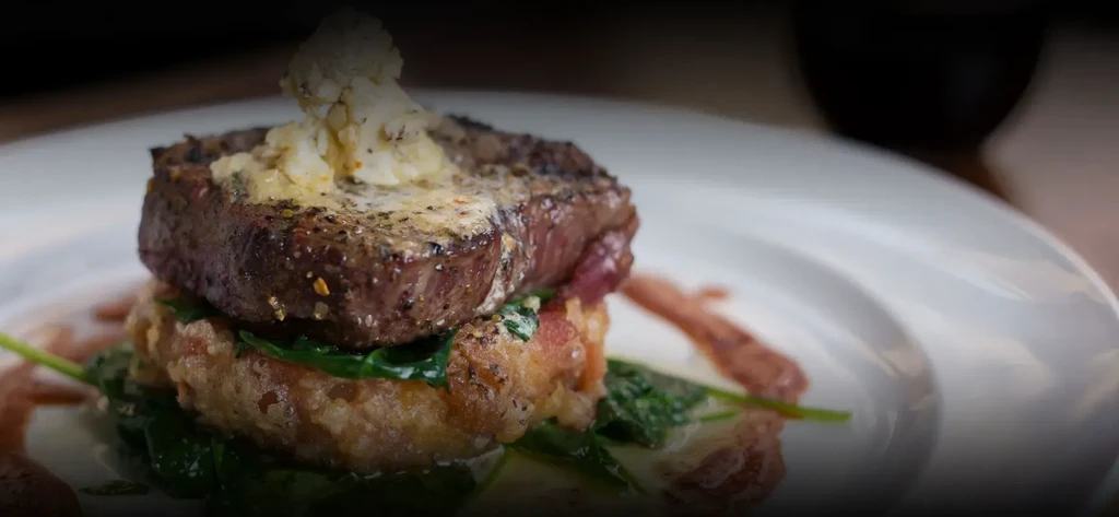 Gourmet steak with herb butter, potato cake, and wilted spinach.