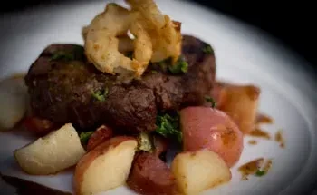 Plated steak topped with crispy onions, roasted potatoes, and herbs.