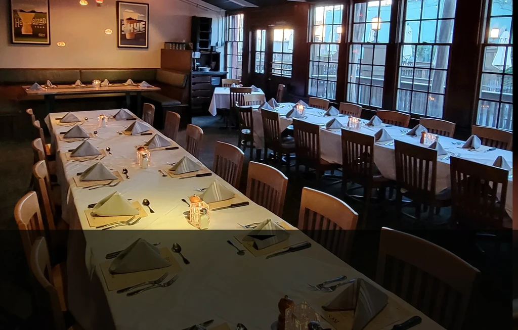 Empty, cozy restaurant interior with set tables and large windows.