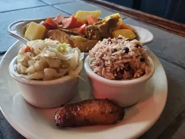 Stewed meat meal with root vegetables, coleslaw, rice, beans, plantain.