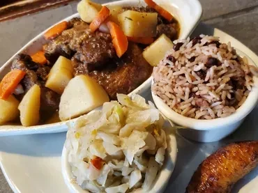 Meat stew with potatoes, carrots, rice, beans, cabbage, and plantain.