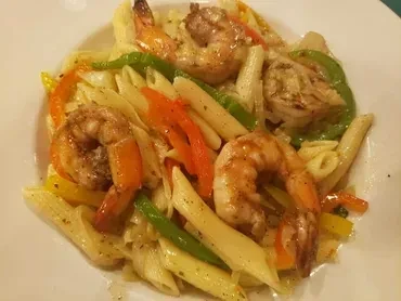 Penne pasta dish with seared shrimp and vibrant bell peppers.