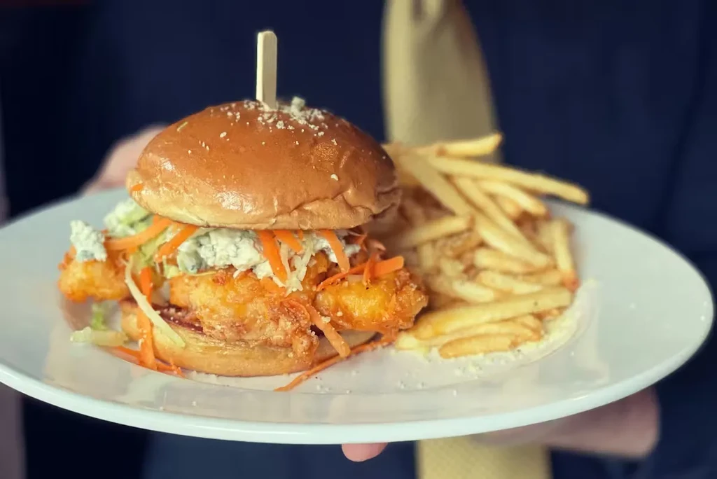 Close-up of a fried sandwich with blue cheese slaw and fries.