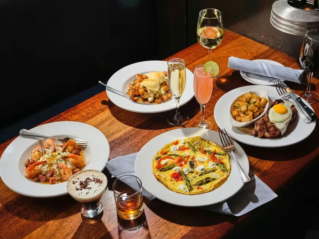 Flat lay: gourmet brunch dishes and drinks on a wooden table.