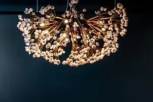 Modern dandelion-burst chandelier with golden structure against a dark background.