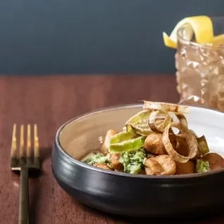 Gnocchi or pasta with green sauce, fried onions, and peppers.