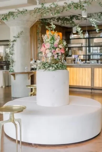 Round white seating with pedestal, holding large pink and white flowers.