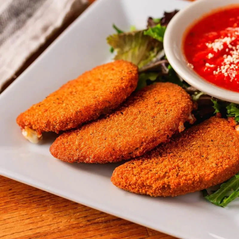 Three golden-fried cheese sticks, one oozing, with marinara sauce.