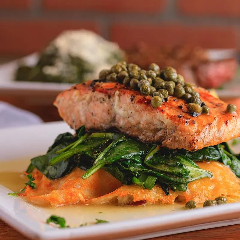 Grilled salmon with capers, spinach, and a layered gratin.