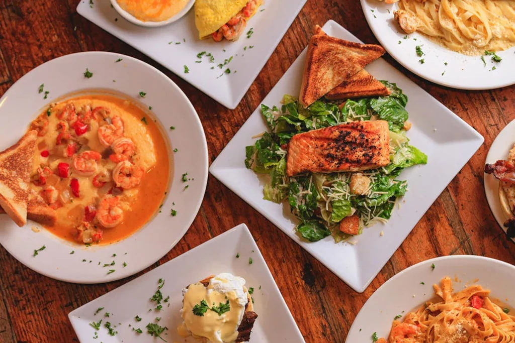 Overhead shot of various plated food dishes on a rustic wooden table.