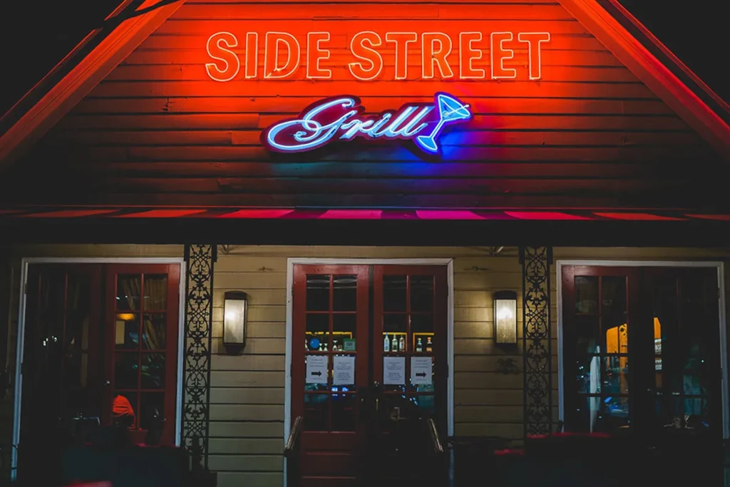 Illuminated Side Street Grill exterior at night with red and blue neon sign.