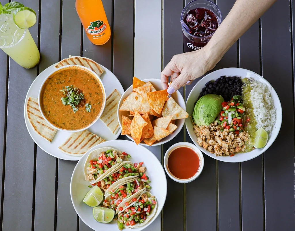Overhead shot of various colorful Mexican dishes and drinks on a table.