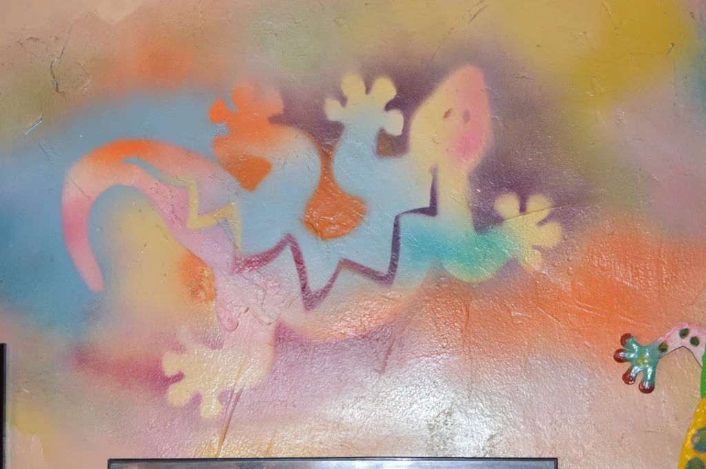 Vibrant mural of stylized geckos on a textured wall with a 3D element.