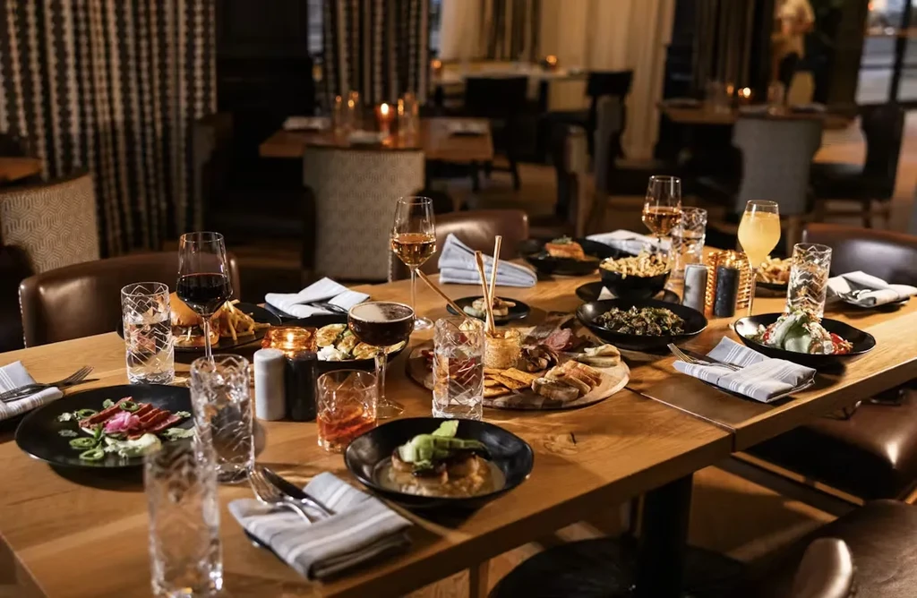 Restaurant table laden with various dishes, drinks, and flickering candles.
