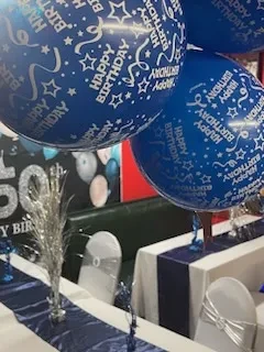 Blue 'Happy Birthday' balloons and 50th birthday table decorations.