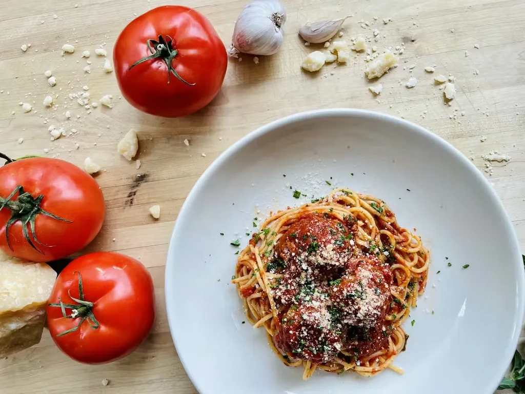 Top-down spaghetti and meatballs with fresh tomatoes, garlic, parmesan.