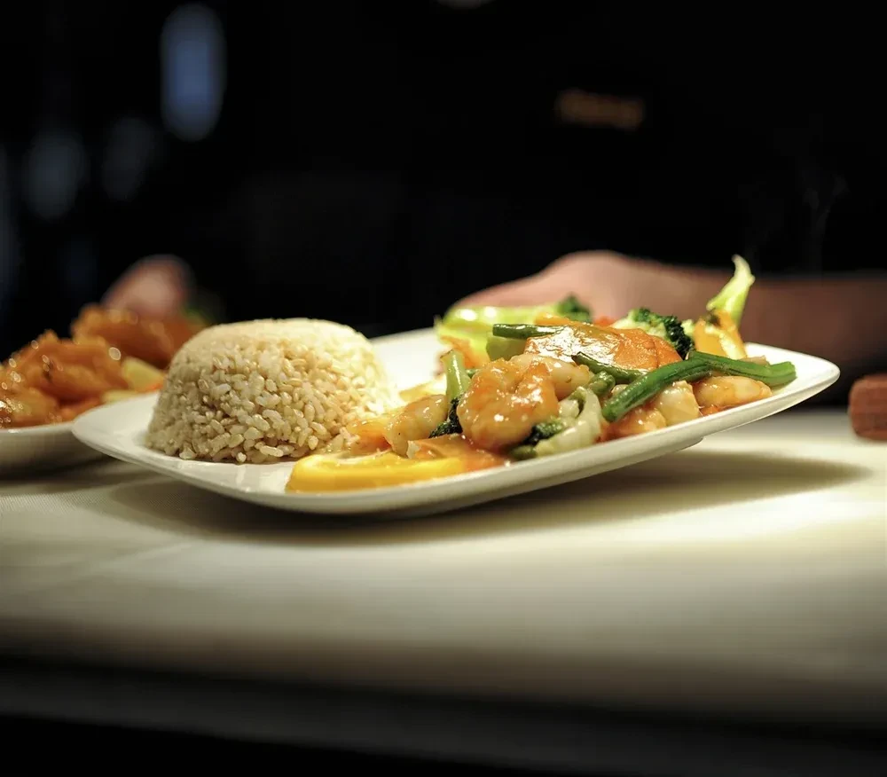 Plated shrimp and vegetable stir-fry with brown rice and lemon.