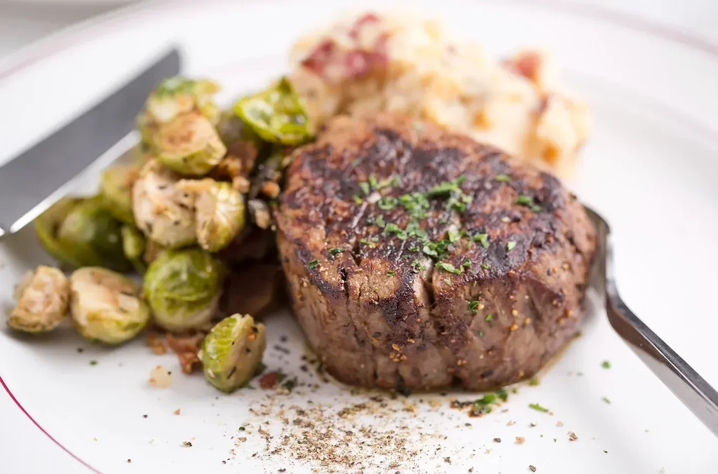 Seared steak with herbs, roasted Brussels sprouts, and creamy side.