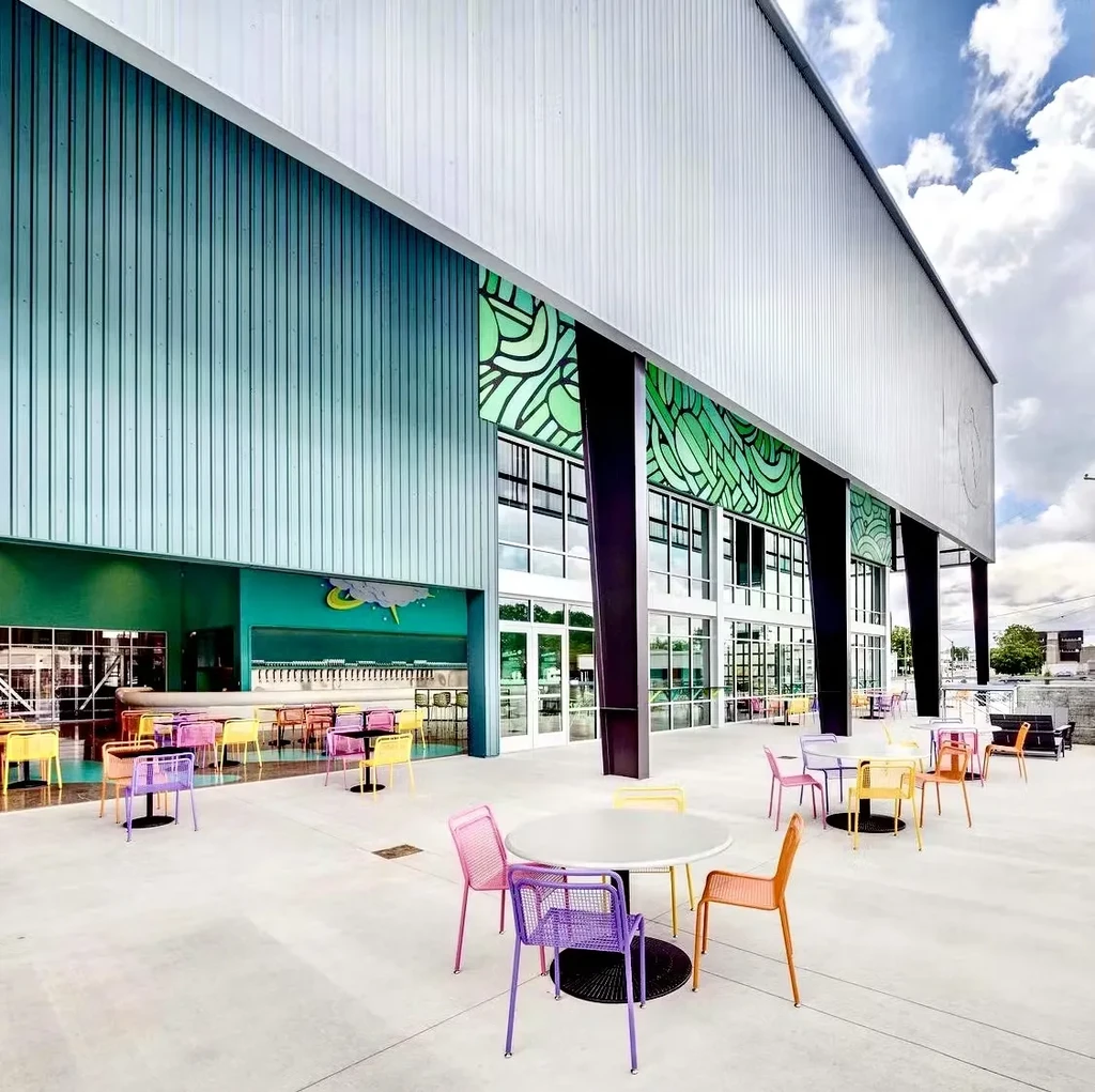 Modern industrial building with two-tone facade and colorful patio chairs.