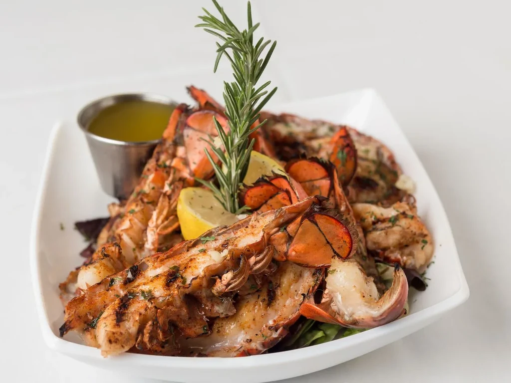 Golden-brown grilled lobster tails, lemon, rosemary, and melted butter.