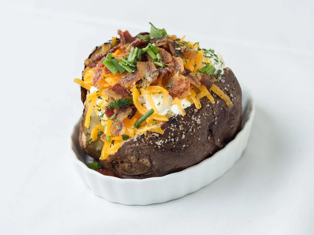 Baked potato loaded with cheese, bacon, sour cream, and chives.