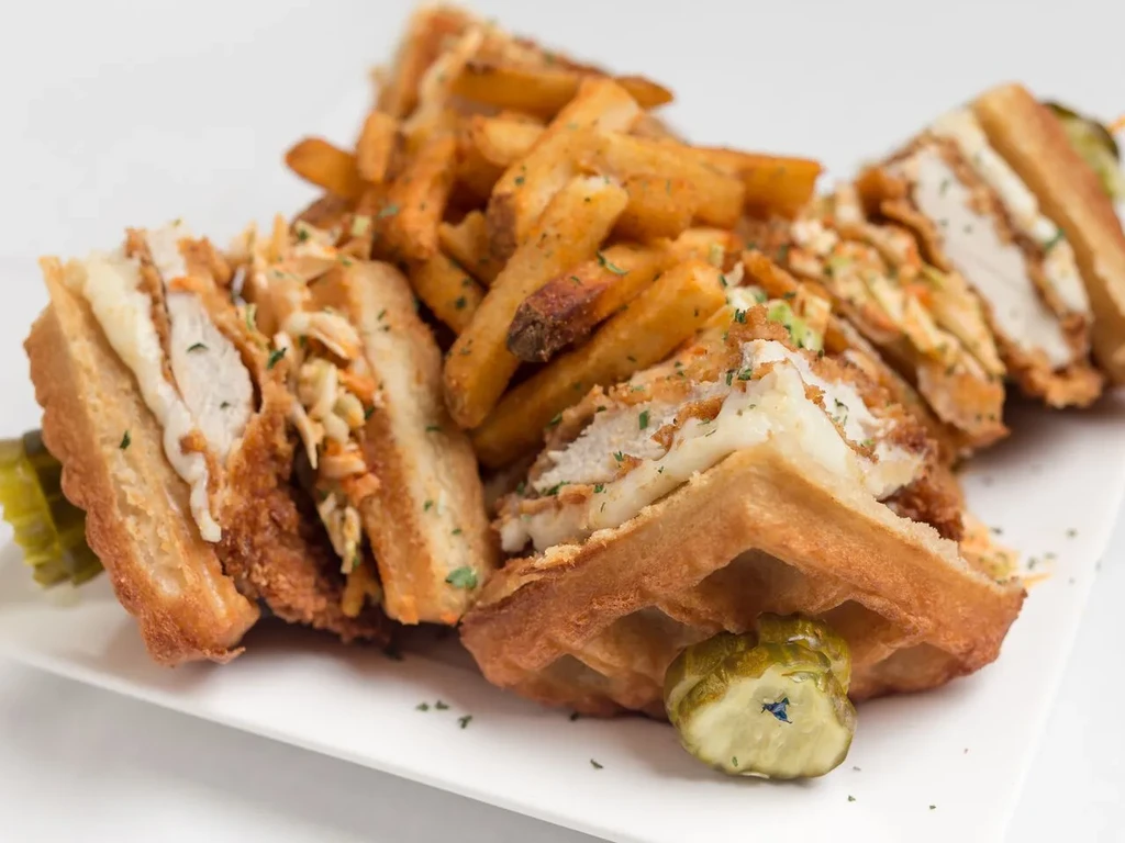 Fried chicken and waffle sandwiches with fries, coleslaw, and pickles.