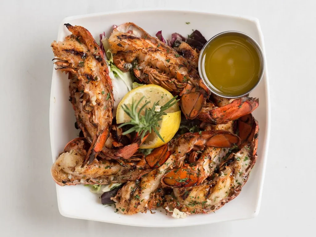 Top-down: Grilled lobster tails, lemon, herbs, and melted butter.