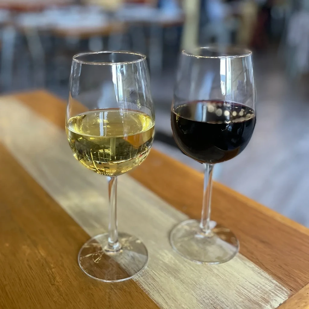 Two glasses of red and white wine on a wooden table.