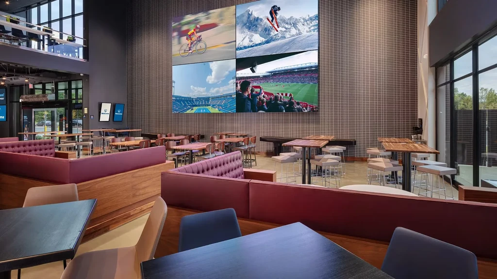 Sleek sports bar interior with a large video wall and empty dining area.