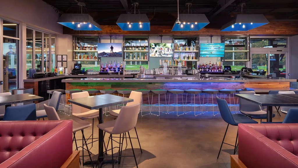 Contemporary bar and restaurant with an illuminated counter, TVs, and seating.
