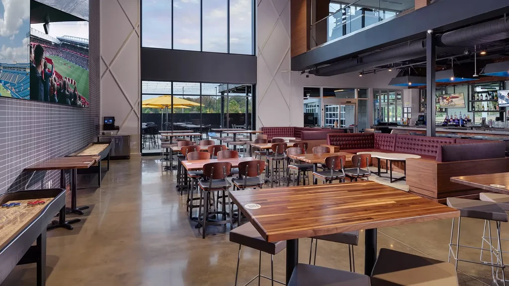 Modern sports bar interior with large screens, shuffleboard, and a full bar.