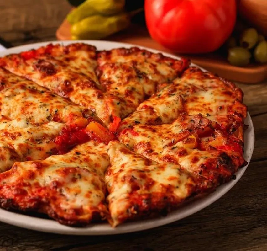 Sliced pizza topped with melted cheese, tomato sauce, and red vegetables.