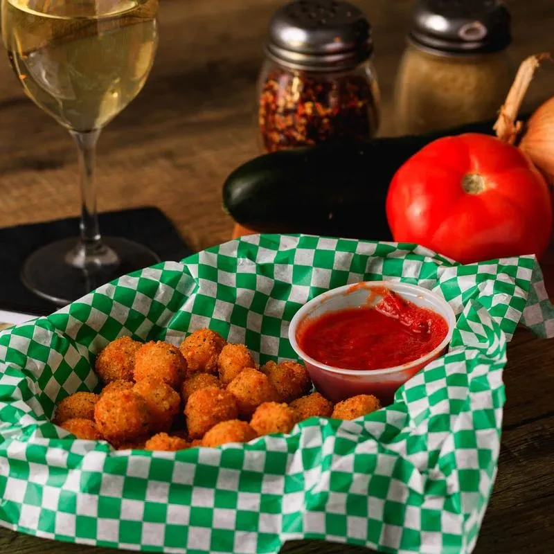 Fried appetizers with red dipping sauce, wine, and fresh ingredients.