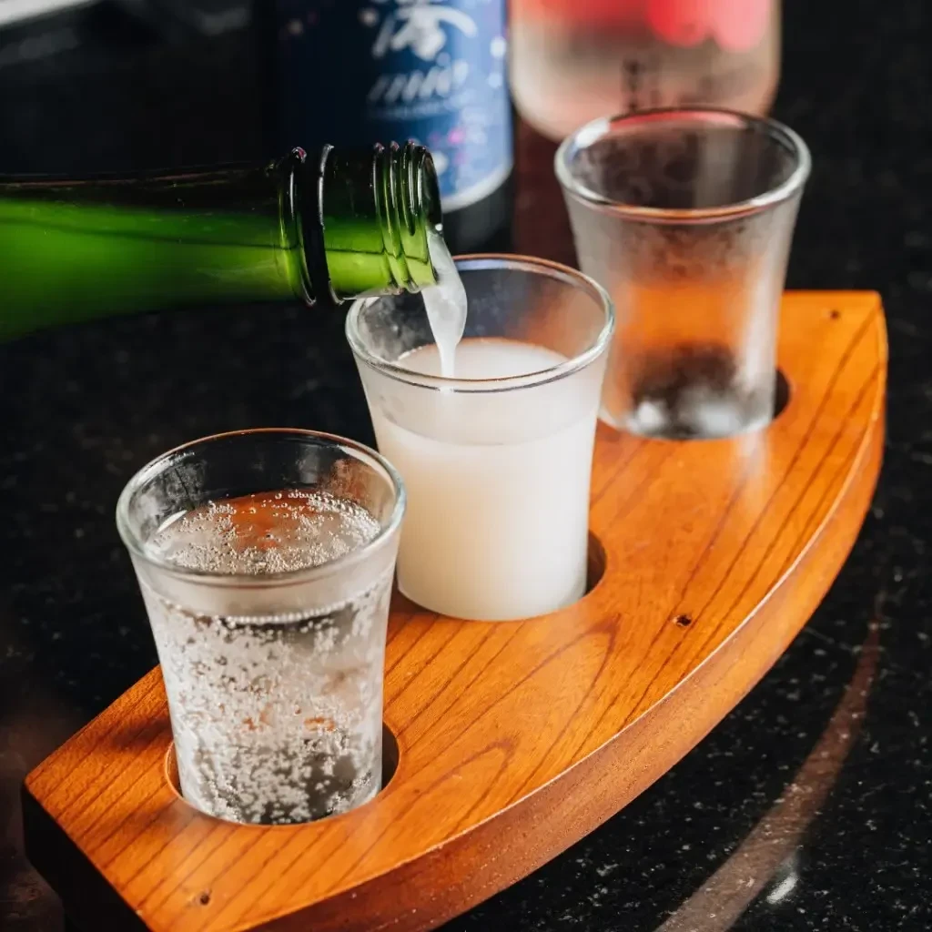 White liquid pours into glass within a three-glass tasting tray.