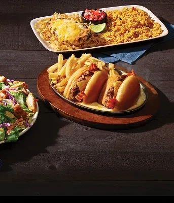 Baked pasta, sliders, fries, and green salad on a dark table.
