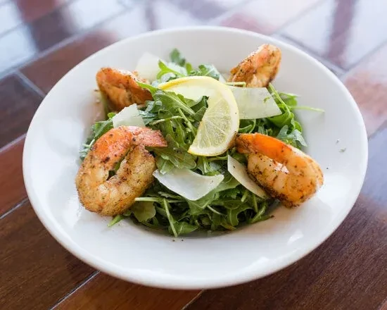 Shrimp and arugula salad with Parmesan cheese and lemon garnish.