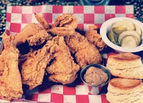 Fried chicken, pickles, stacked biscuits, and dipping sauce on a tray.