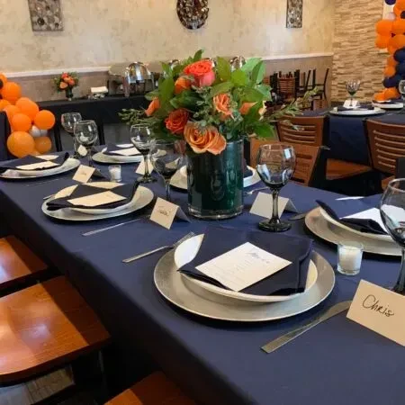 Set restaurant table with orange roses centerpiece and "Chris" place card.