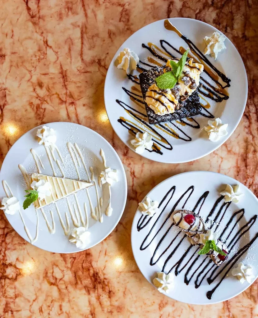 Three distinct dessert plates on a polished marble countertop.