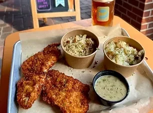 Crispy fried meal with two sides, green dip, and beer.