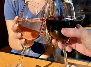 Two hands clinking wine glasses, one red, one white.